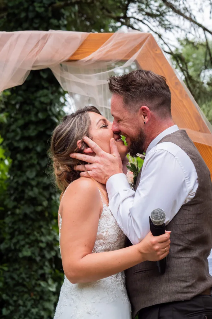Photo des mariés s'embrassant après l'échange des voeux lors de la cérémonie laïque au château du Croisillat à Caraman (31) - Mariage d’Élodie et Julien - 2025 - Photographe à Saint-Gaudens (31) Marc Villard / VILMAGE