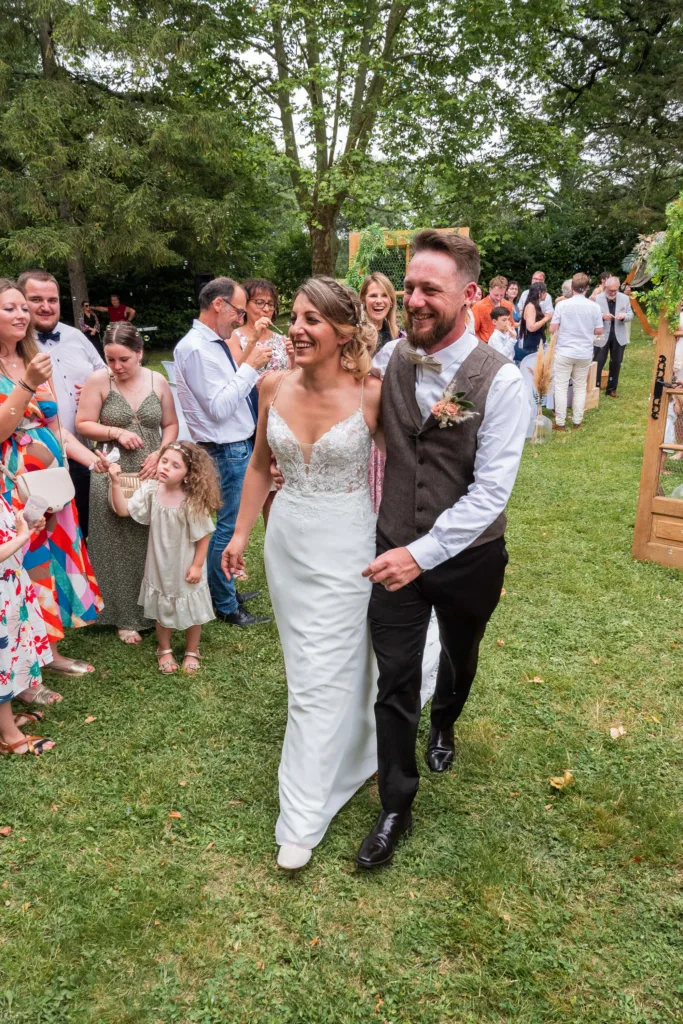 Photo de la sortie des mariés à la fin de la cérémonie laïque dans le parc du château du Croisillat à Caraman (31) - Mariage d’Élodie et Julien - 2025 - Photographe à Saint-Gaudens (31) Marc Villard / VILMAGE