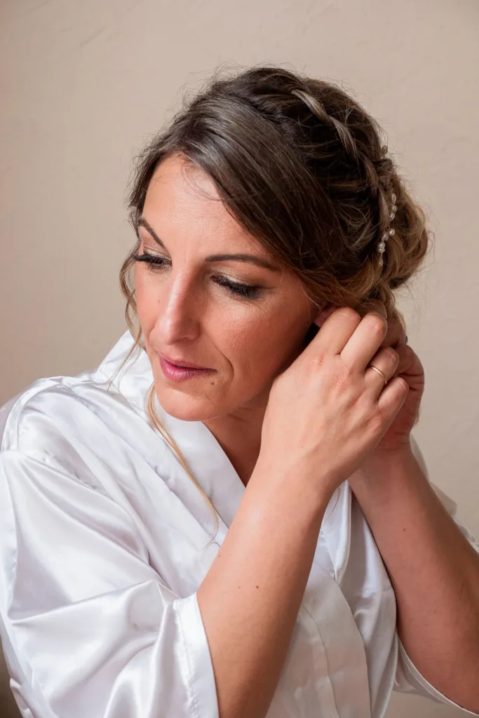 Photo de la mariée attachant sa boucle d'oreille dans le château du Croisillat à Camaran (31) - Mariage d’Élodie et Julien - 2025 - Photographe à Saint-Gaudens (31) Marc Villard / VILMAGE
