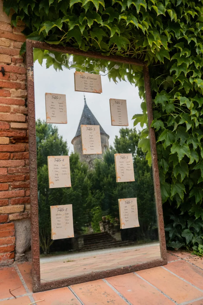 Photo du plan de table dans un miroir reflétant la tour du château du Croisillat à Caraman (31) - Mariage d’Élodie et Julien - 2025 - Photographe à Saint-Gaudens (31) Marc Villard / VILMAGE
