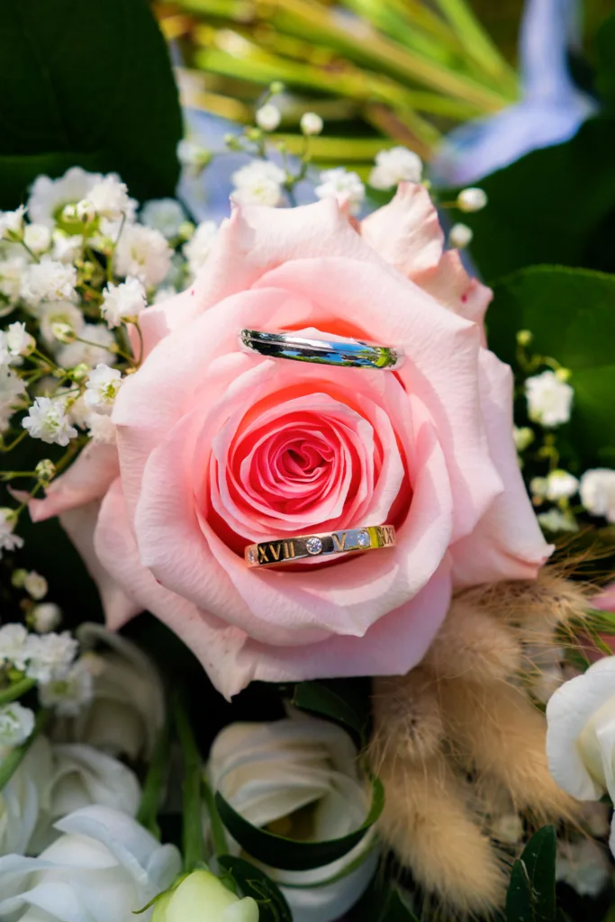 Photo des alliances des mariés posées sur une rose rose à la Grange Marcaoue à Bézéril (32 - Gers) - Mariage d'Emma et Mickaël - 2025 - Photographe à Saint-Gaudens (31) Marc Villard / VILMAGE