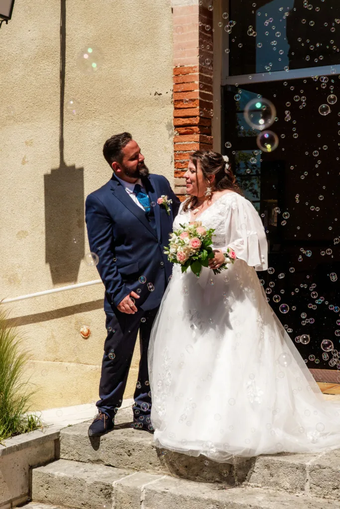 Photo de la sortie des mariés à la mairie de Gimont (32) dans un nuage de bulles - Mariage d'Emma et Mickaël - 2025 - Photographe à Saint-Gaudens (31) Marc Villard / VILMAGE