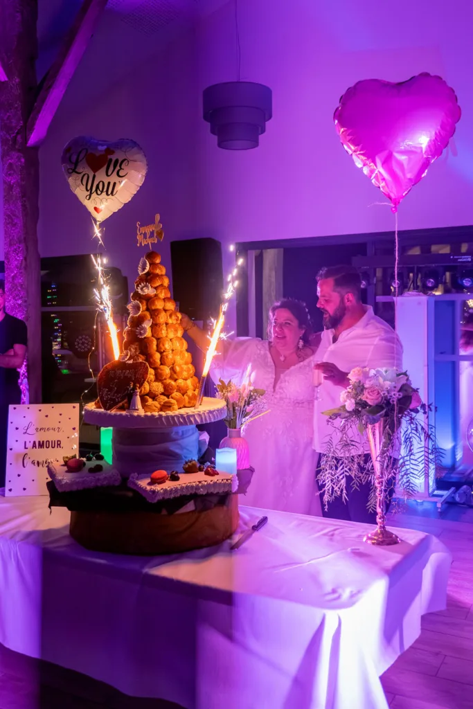Photo des mariés devant leur pièce montée de choux au domaine de la Grange Marcaoue à Bézéril (32 - Gers) - Mariage d'Emma et Mickaël - 2025 - Photographe à Saint-Gaudens (31) Marc Villard / VILMAGE