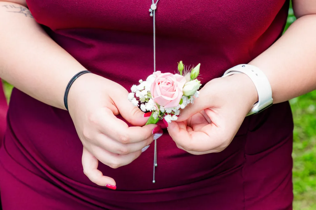 Photo d'une témoin tenant la boutonnière du marié au domaine de la Grange Marcaoue à Bézéril (32 - Gers) - Mariage d'Emma et Mickaël - 2025 - Photographe à Saint-Gaudens (31) Marc Villard / VILMAGE
