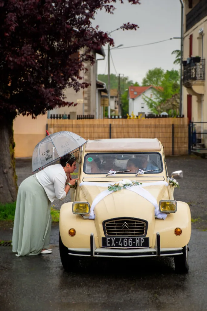 Photo des mariés dans une 2CV Citroën avec une témoin à l'extérieur - Mariage d'Isabelle et Jérôme - 2025 - Photographe à Saint-Gaudens (31) Marc Villard / VILMAGE
