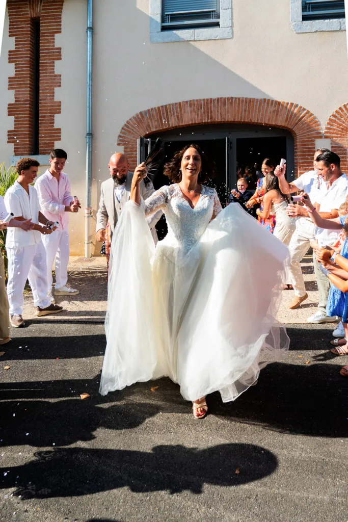 Photo des mariés sortant de la mairie de Villeneuve de Rivière (31) sous les ovations et les confettis - Mariage de Sophie et Alain - 2025 - Photographe à Saint-Gaudens (31) Marc Villard / VILMAGE