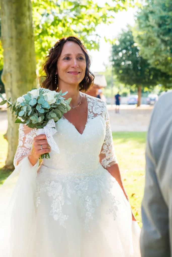Photo de la mariée souriante dans le parc de l'église de Villeneuve-de-Rivière (31) - Mariage de Sophie et Alain - 2025 - Photographe à Saint-Gaudens (31) Marc Villard / VILMAGE